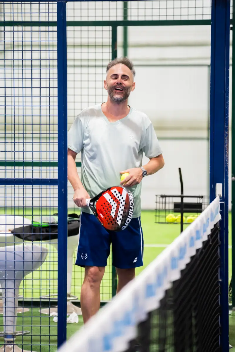 Iván smiling at the net on an indoor padel court