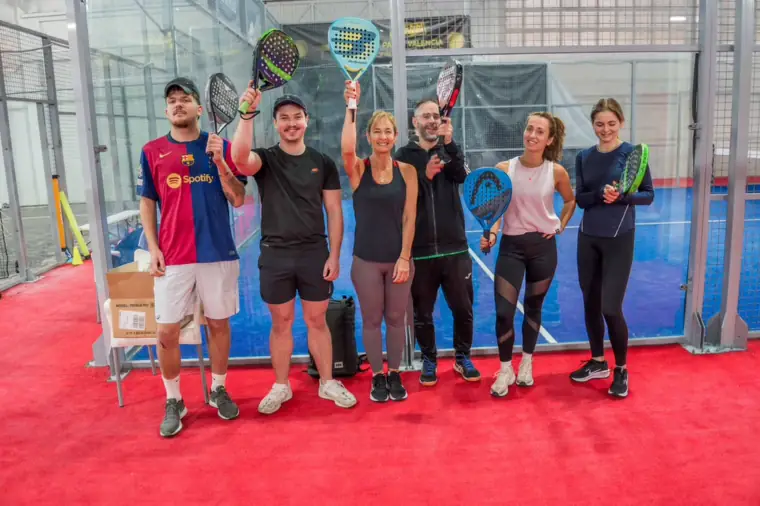 Six smiling players with their rackets up after a Saturday Social