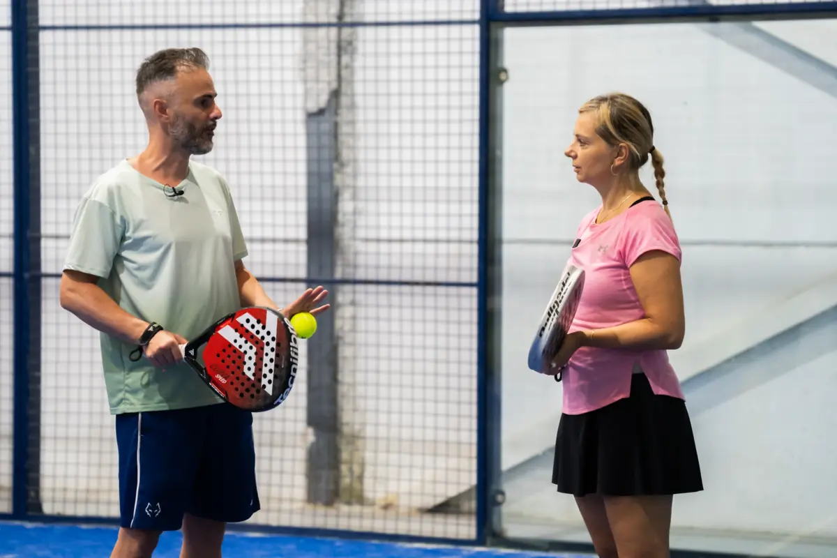 The coach explaining a drill to a participant before a padel session