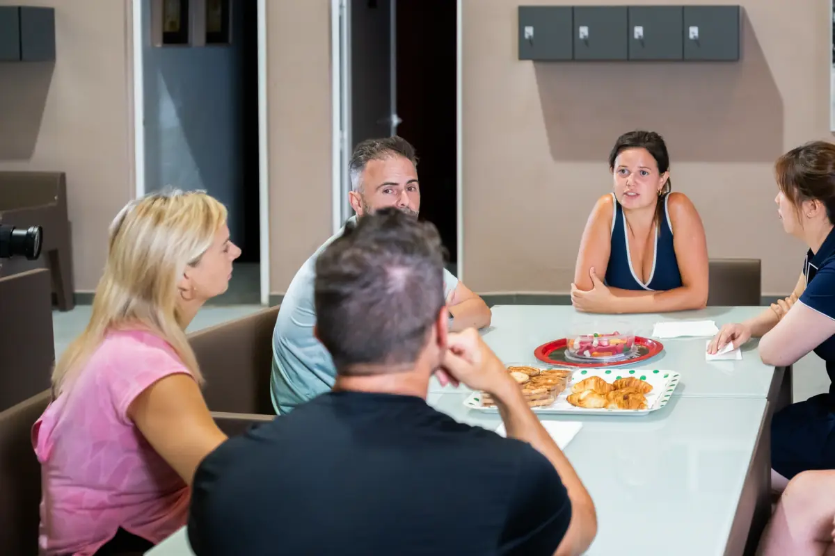 A team chatting around a table with snacks after a padel session